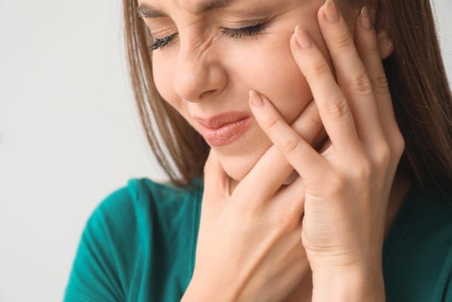 אישה סובלת מכאב שיניים בשל שן בינה כלואה